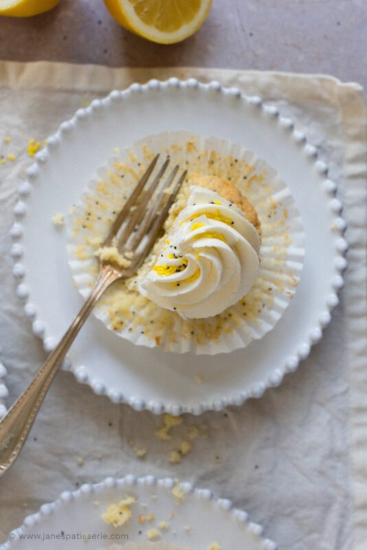 A lemon and poppyseed cupcake with a fork and a plate