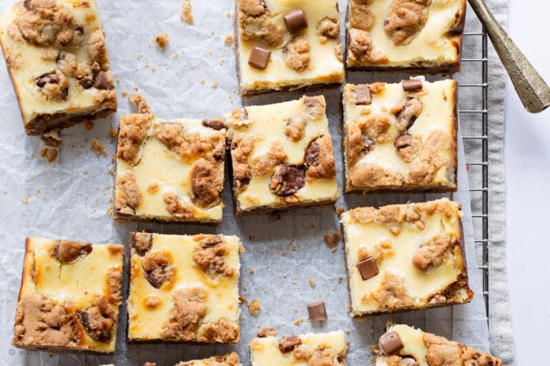 The tray of cheesecake cookie bars cooling on a wire rack with some missing