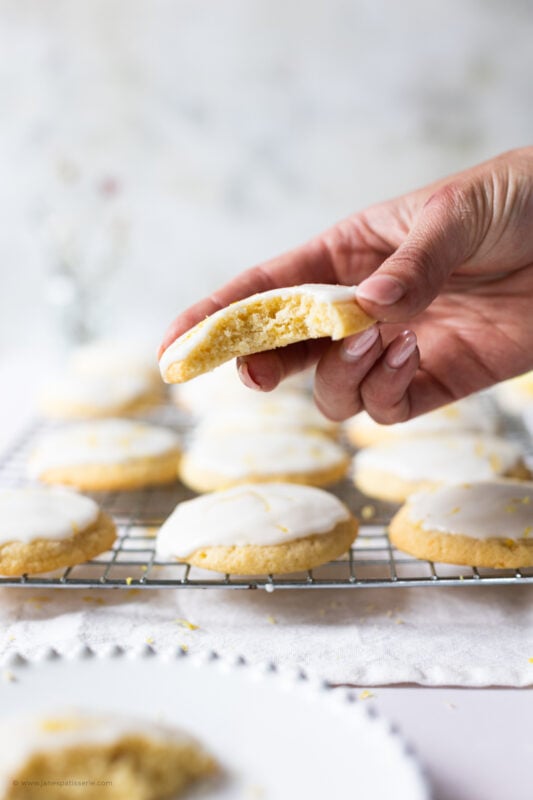 A hand holding a bitten glazed cookie
