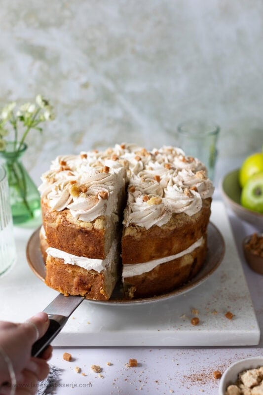 a knife cutting into and taking a slice of apple crumble cake