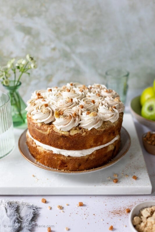 A whole apple crumble cake with buttercream icing on a plate