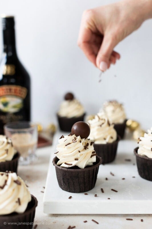 Sprinkles over baileys cupcakes with baileys bottle in the background