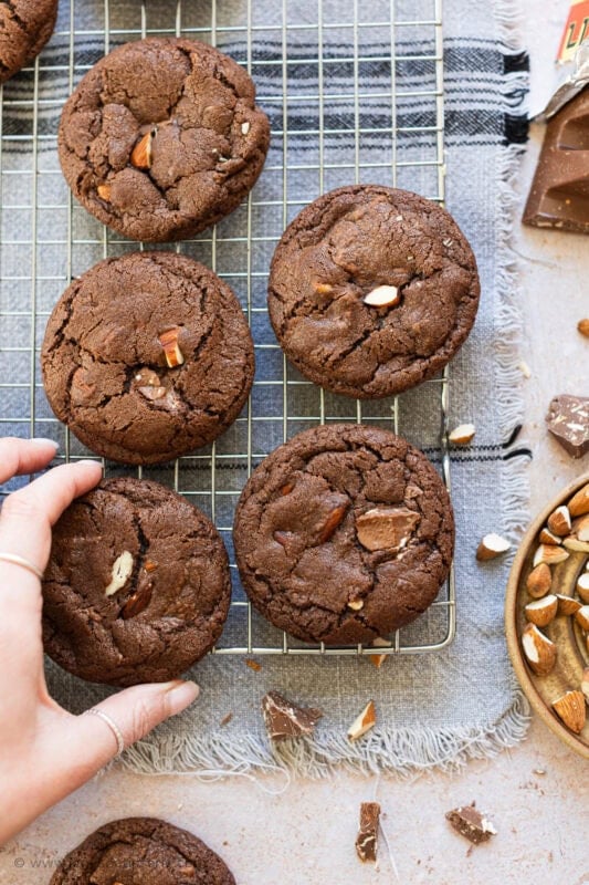 A hand reaching for a Toblerone cookie from a cooling rack