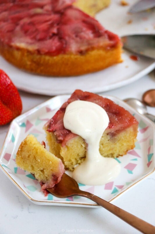 A fork cutting into a slice of strawberry upside down cake.