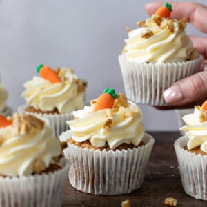 A hand taking a carrot cake cupcake
