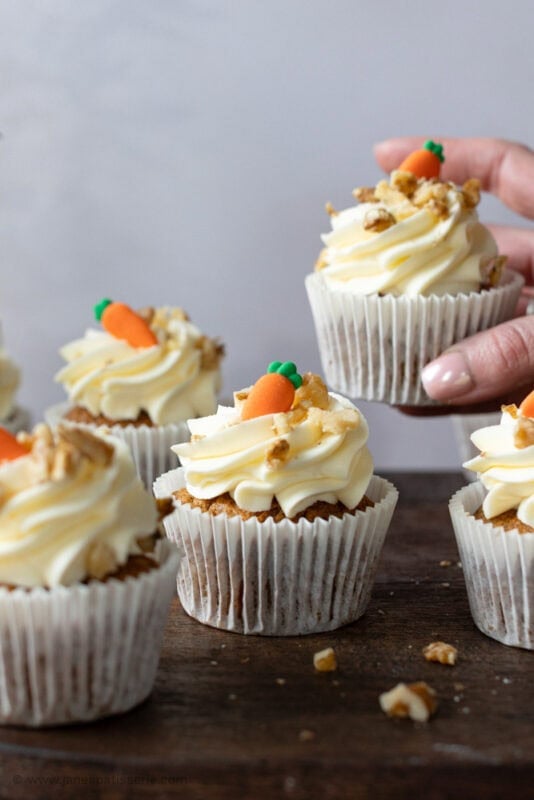 A hand taking a carrot cake cupcake