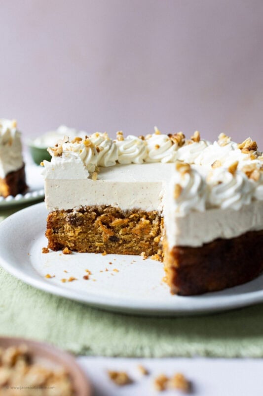 A slice missing of a whole carrot cake cheesecake