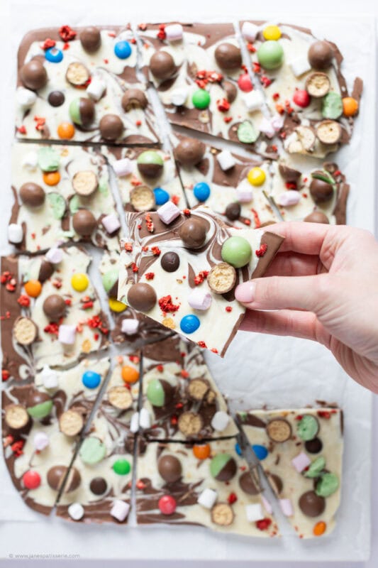 A hand holding one piece of chocolate bark