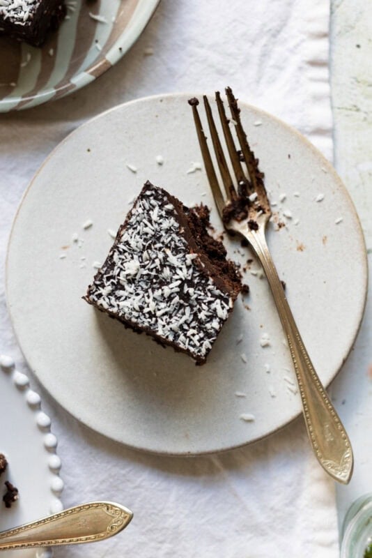 A plate with a coconut brownie with a bite missing