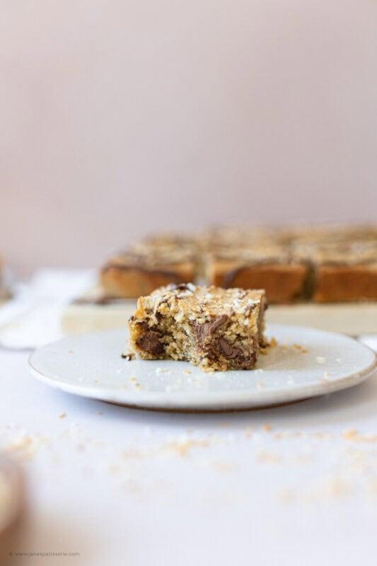 A single Coconut Chocolate Blondie on a white plate