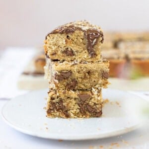 Three Coconut Chocolate Blondies stacked on a plate