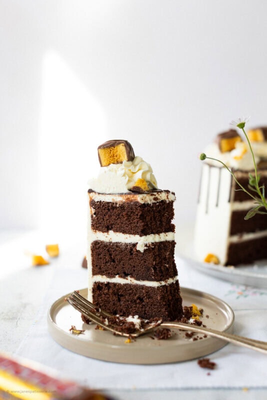 A bite missing from a slice of crunchie drip cake