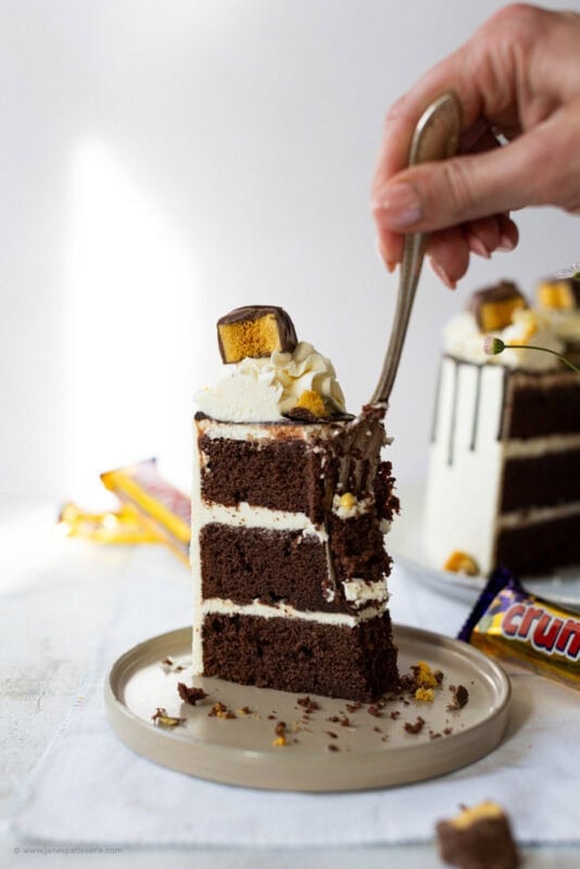 A fork going into a slice of Crunchie Drip Cake
