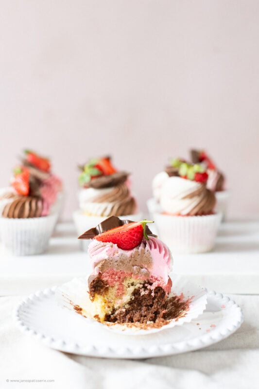 A bite missing from a Neapolitan Cupcake showing the sponge