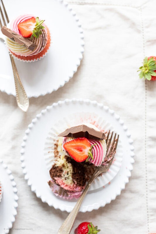 A half eaten Neapolitan Cupcake on a white plate