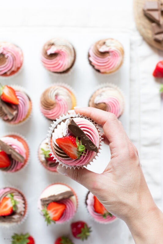 A hand holding a Neapolitan Cupcake