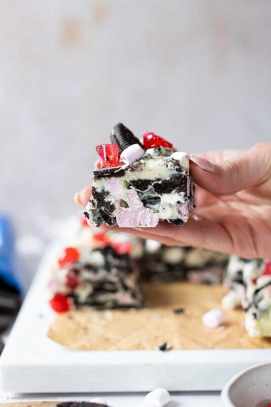 A hand holding a slice of Oreo Rocky Road