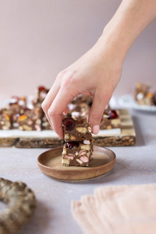 A hand taking a Rocky Road Fudge piece from a plate