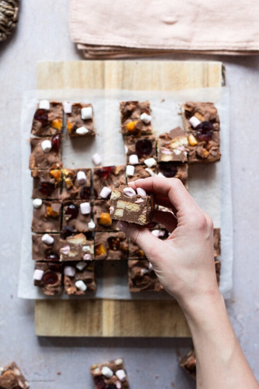A hand holding a piece of Rocky Road Fudge above the rest