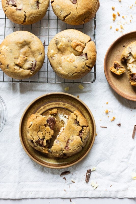 A baking tray of Salted Caramel Cheesecake Cookies and one on a plate