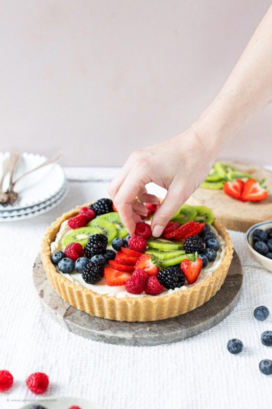 A hand decorating the Easy Fruit Tart