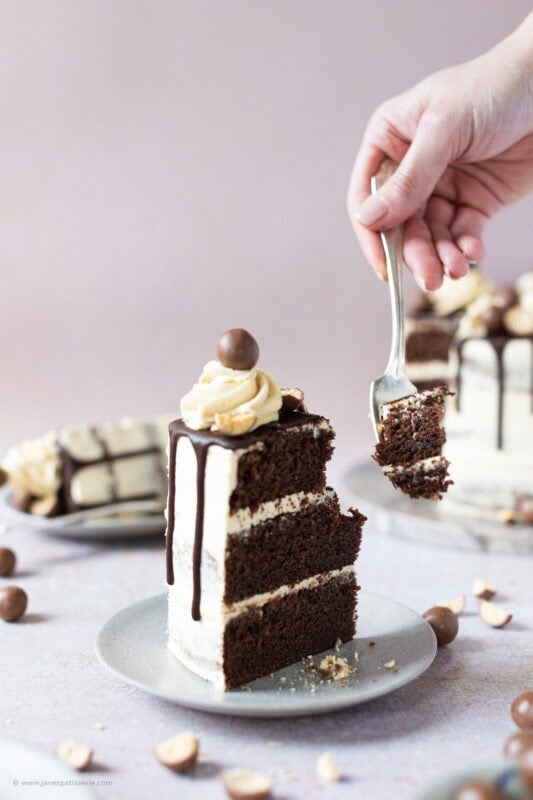 A fork slicing into a slice of Malteser Drip Cake