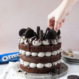 A hand decorating a finished Oreo Cake