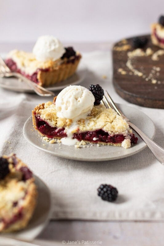 Close up of Apple and Blackberry Crumble Pie on a plate with ice cream and a fork