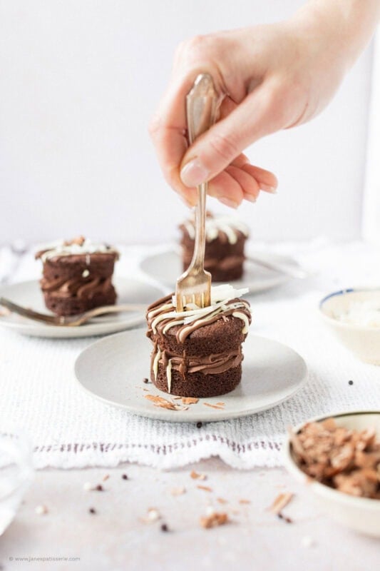 A hand placing a fork into a Mini Chocolate Cake on a plate