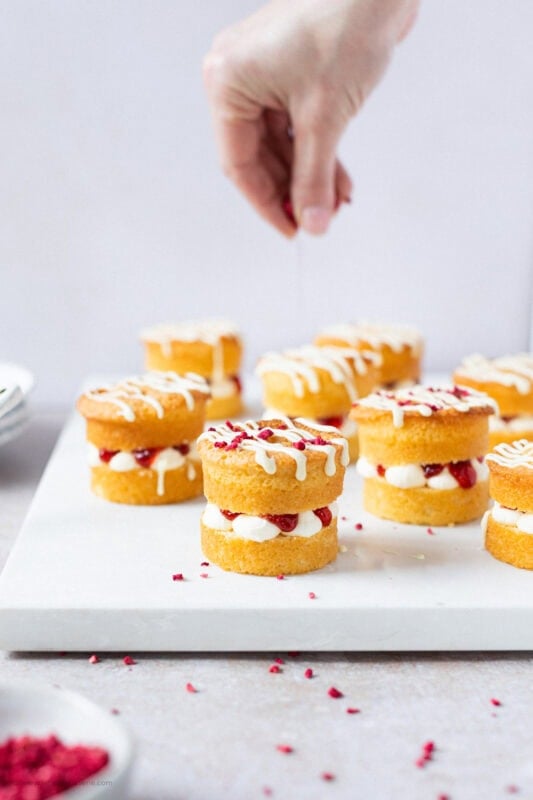 A hand putting the final decorations on a mini Victoria sponge cake