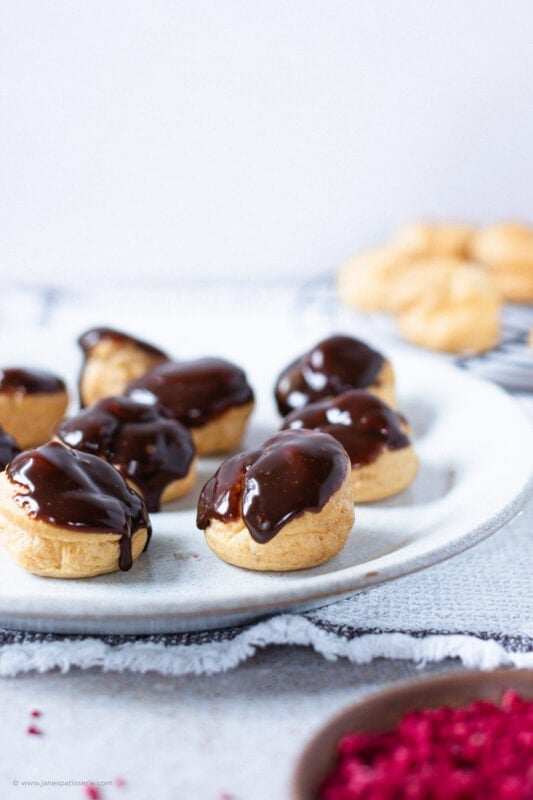 A plate of unfinished profiteroles waiting to be decorated