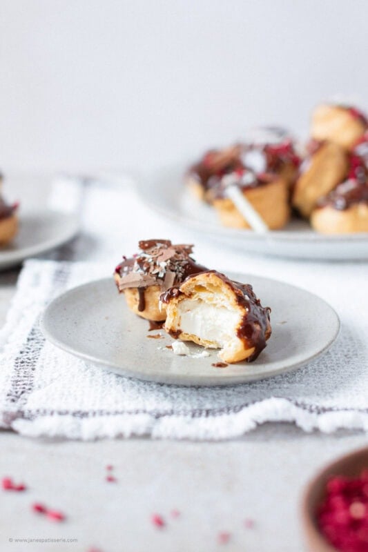 A bite taken from a single profiterole on a plate