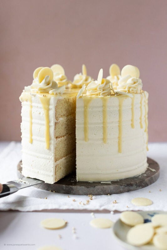 A slice being taken from a White chocolate drip cake