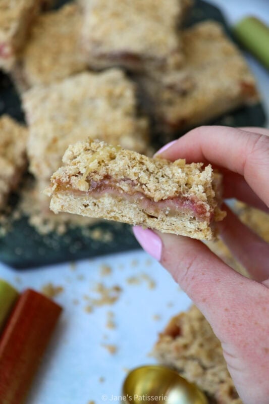 A hand holding an half eaten Rhubarb Crumble Bar