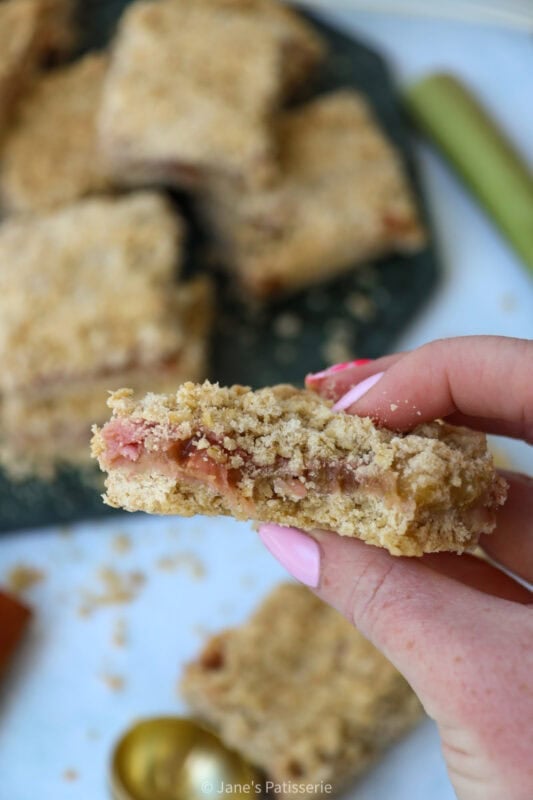 A hand holding a square of Rhubarb Crumble Bar
