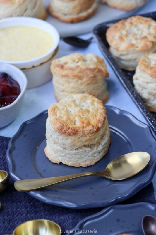 A freshly baked, uncut buttermilk scone on a plate with a spoon.