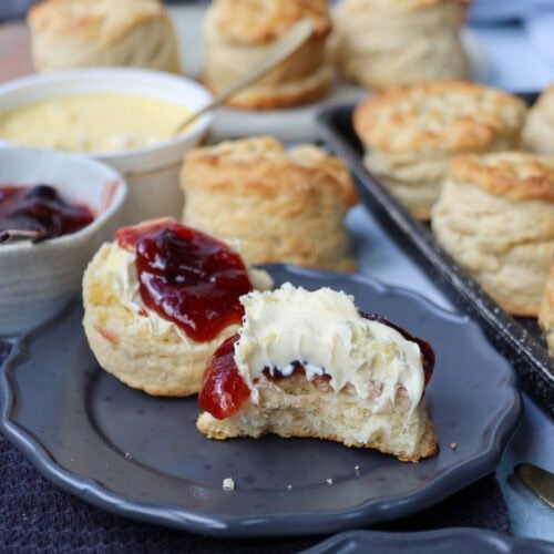 A freshly baked Buttermilk Scones slathered in jam and clotted cream.