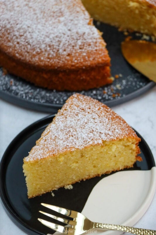 A slice of freshly dusted Lemon Olive Oil Cake on a plate