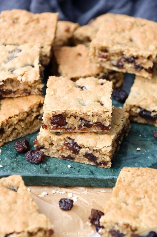 Two Oatmeal Raisin Bars stacked on a green chopping board