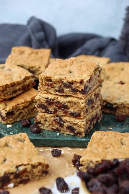 Three Oatmeal Raisin Bars stacked on a chopping board