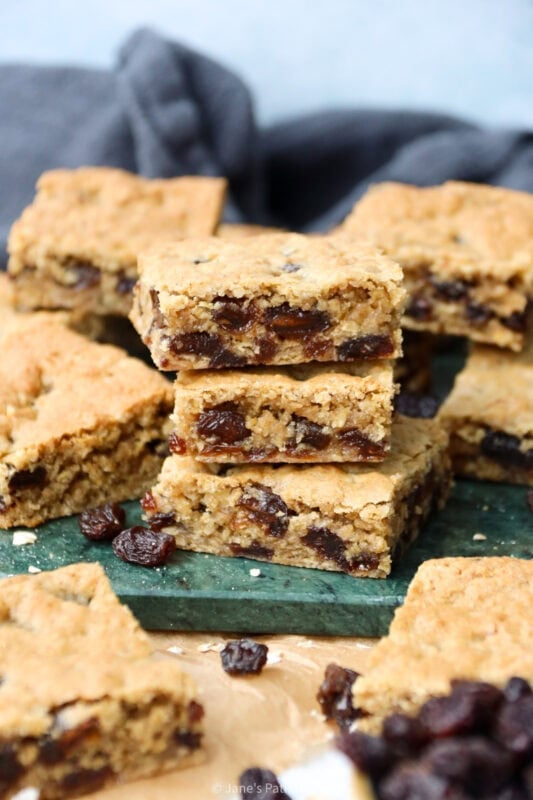 A stack of Oatmeal Raisin Bars on a green chopping board